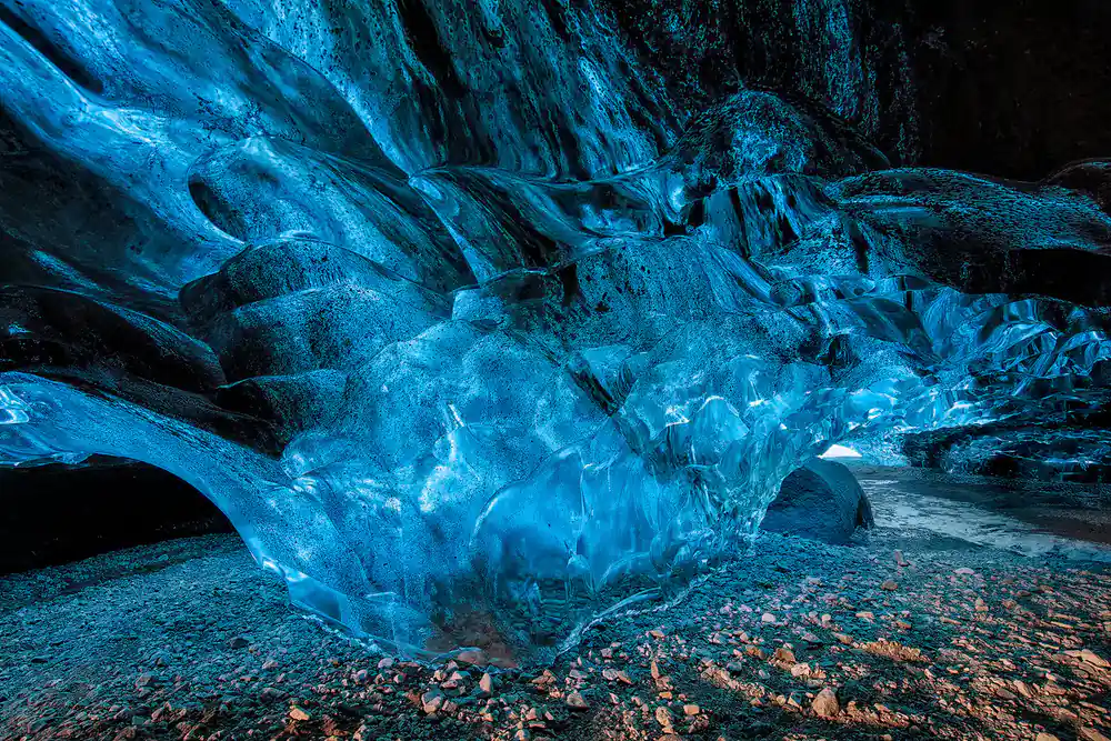 Blue ice cave interior with rocky ground floor