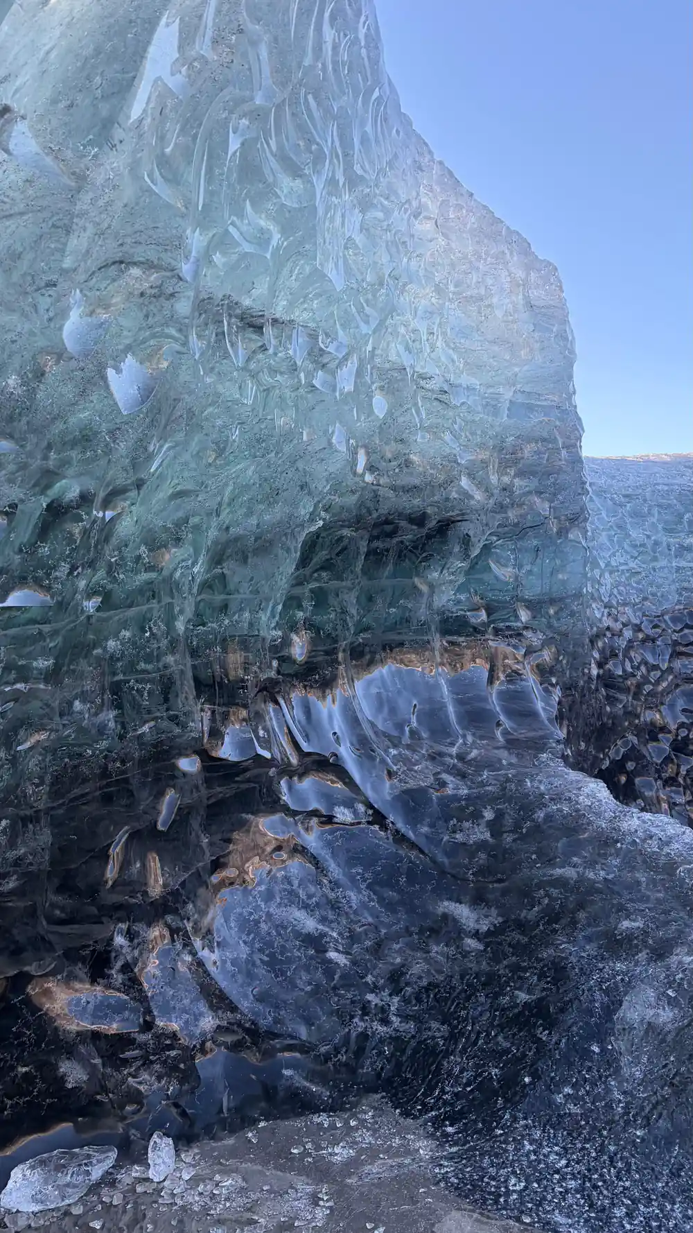 Blue ice wall with dark rocky debris and formations