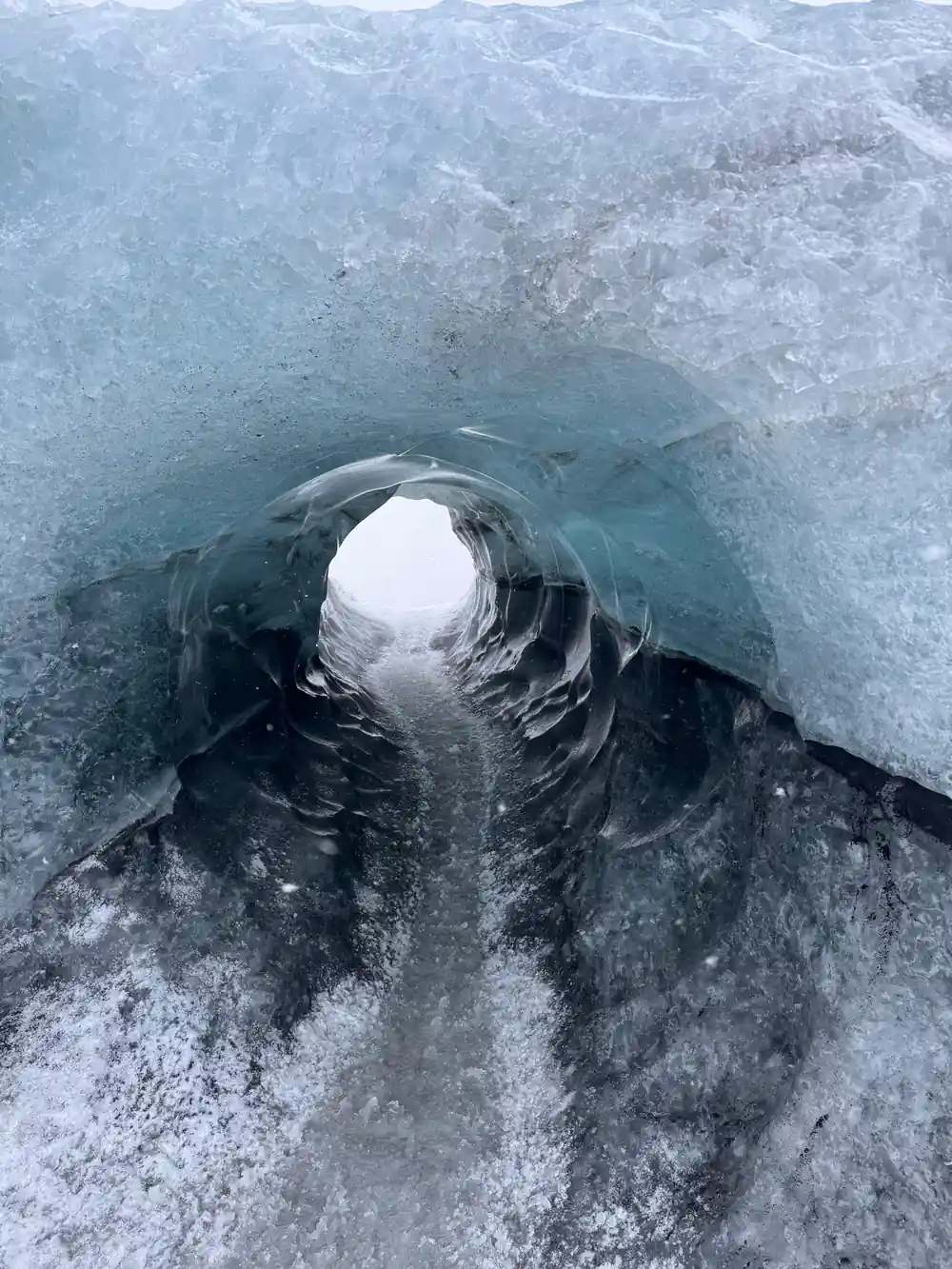 Blue-white circular ice cave opening from above view