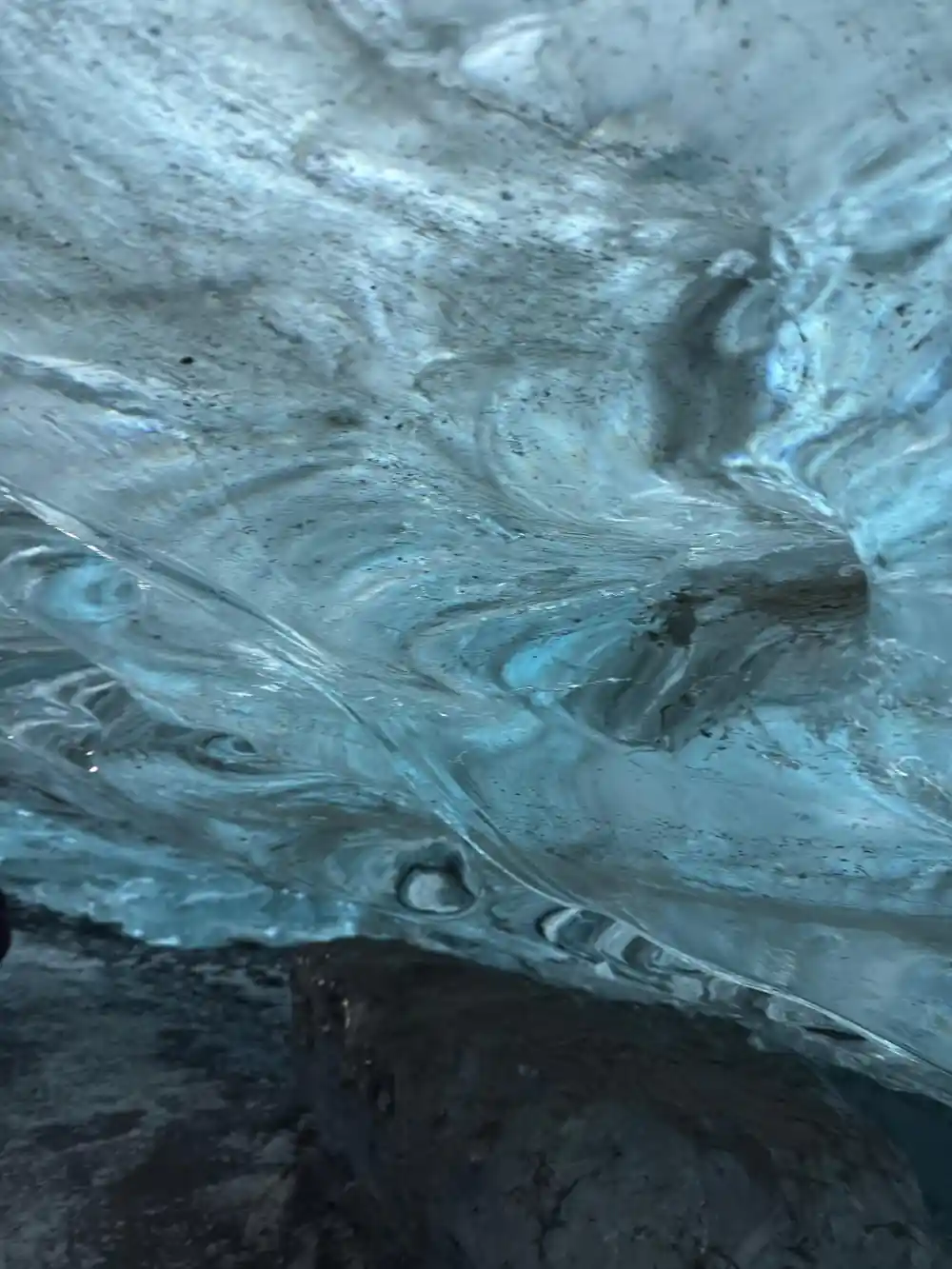 Circular opening in glacier ice ceiling with light