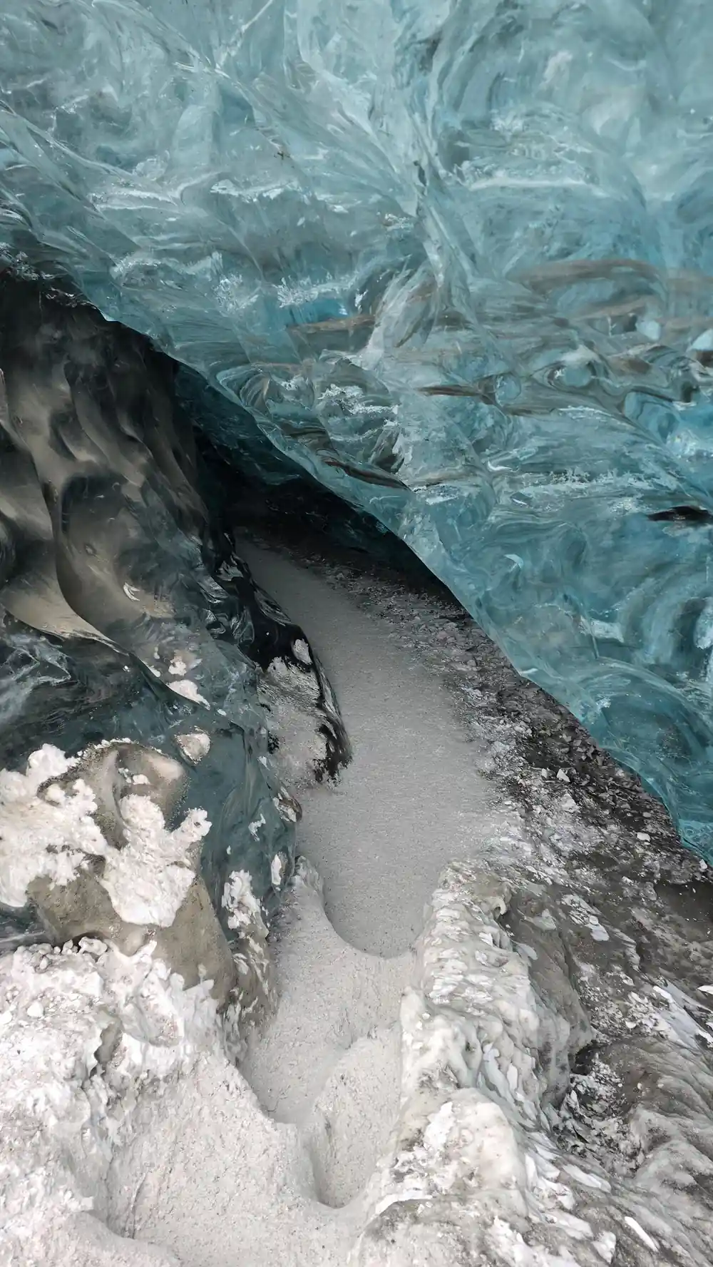 Curved ice cave passage with turquoise walls overhead