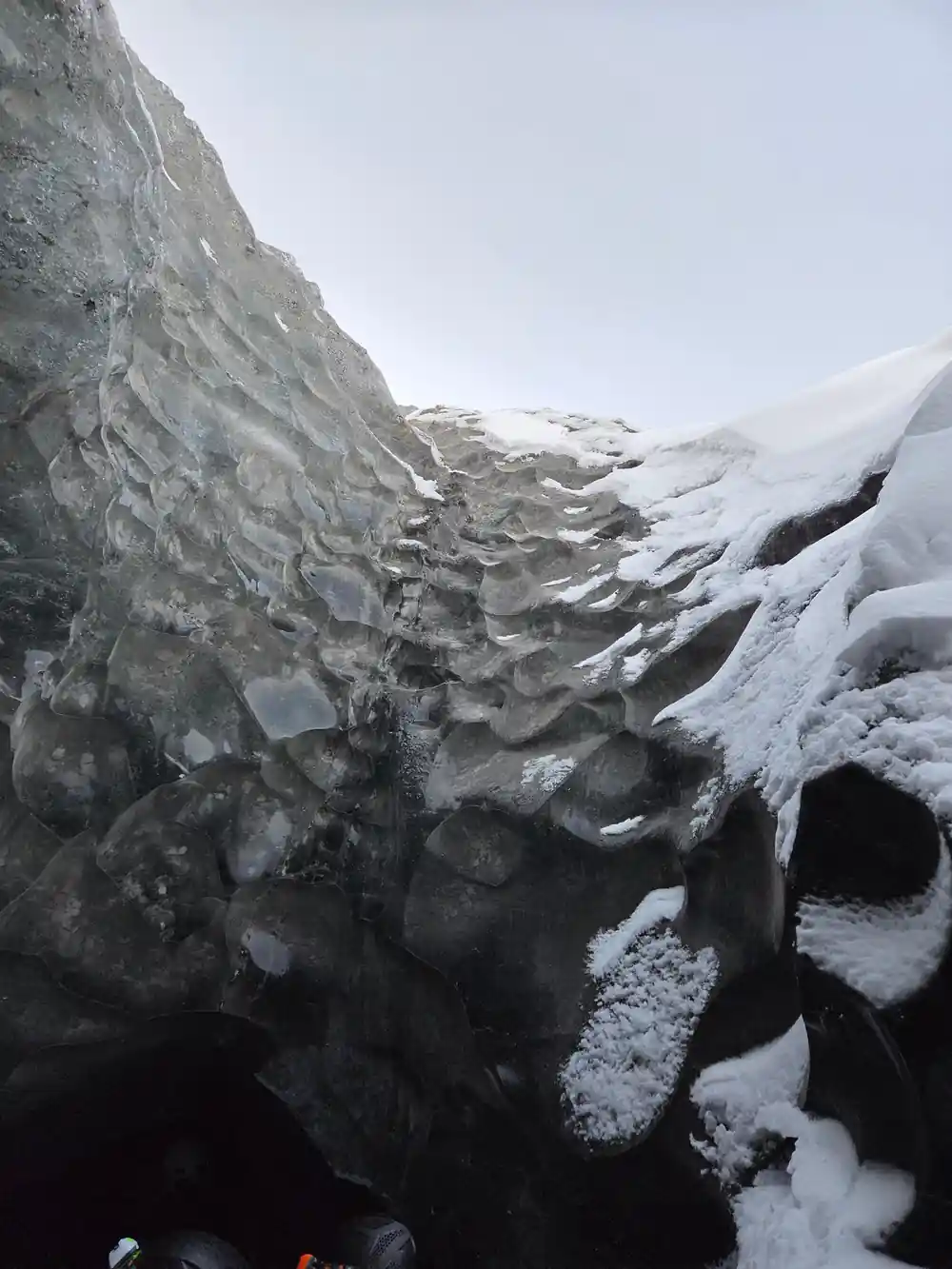 Glacial ice wall with layered formations and snow patches