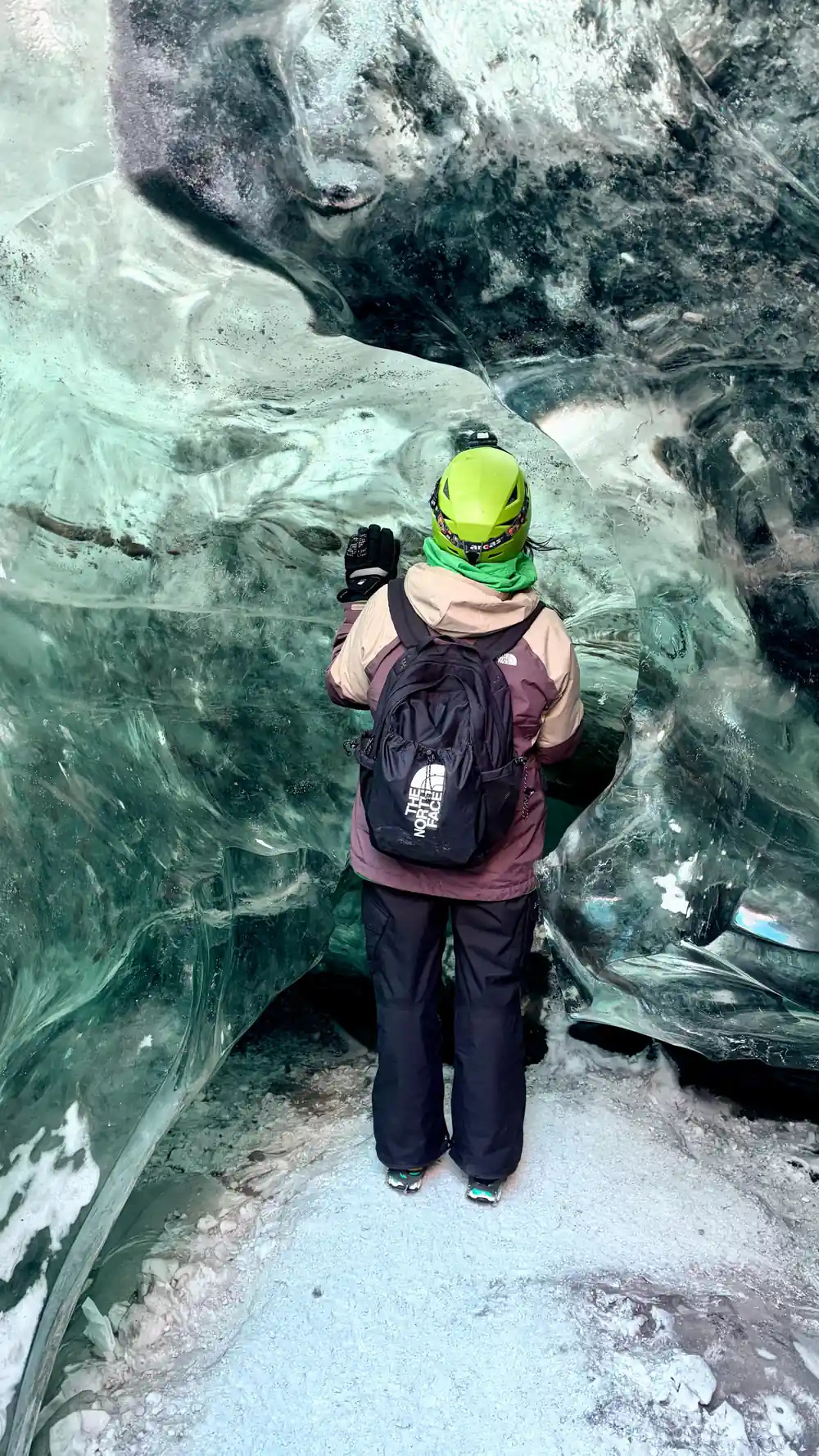 Hiker in yellow helmet standing in ice cave