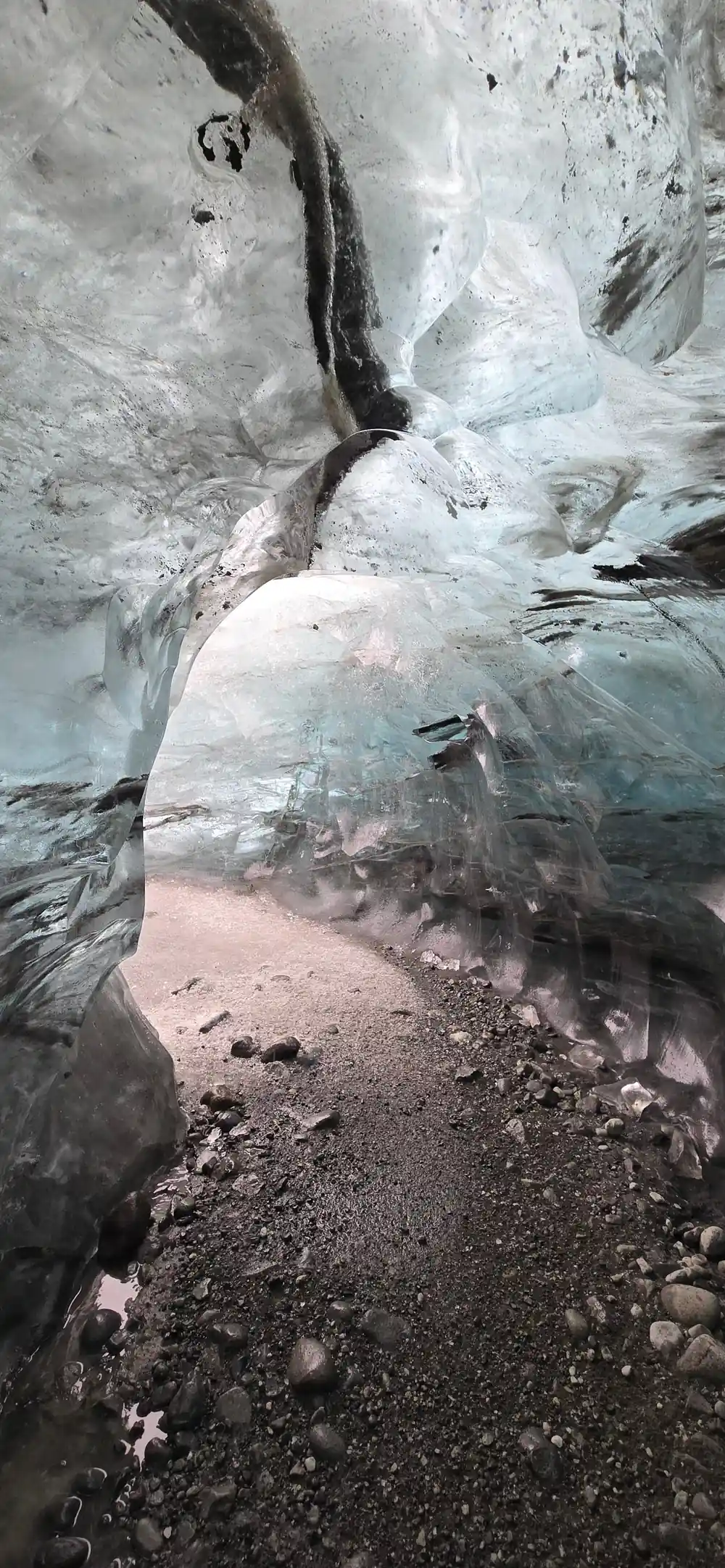 Ice cave interior with blue ice walls and rocky floor