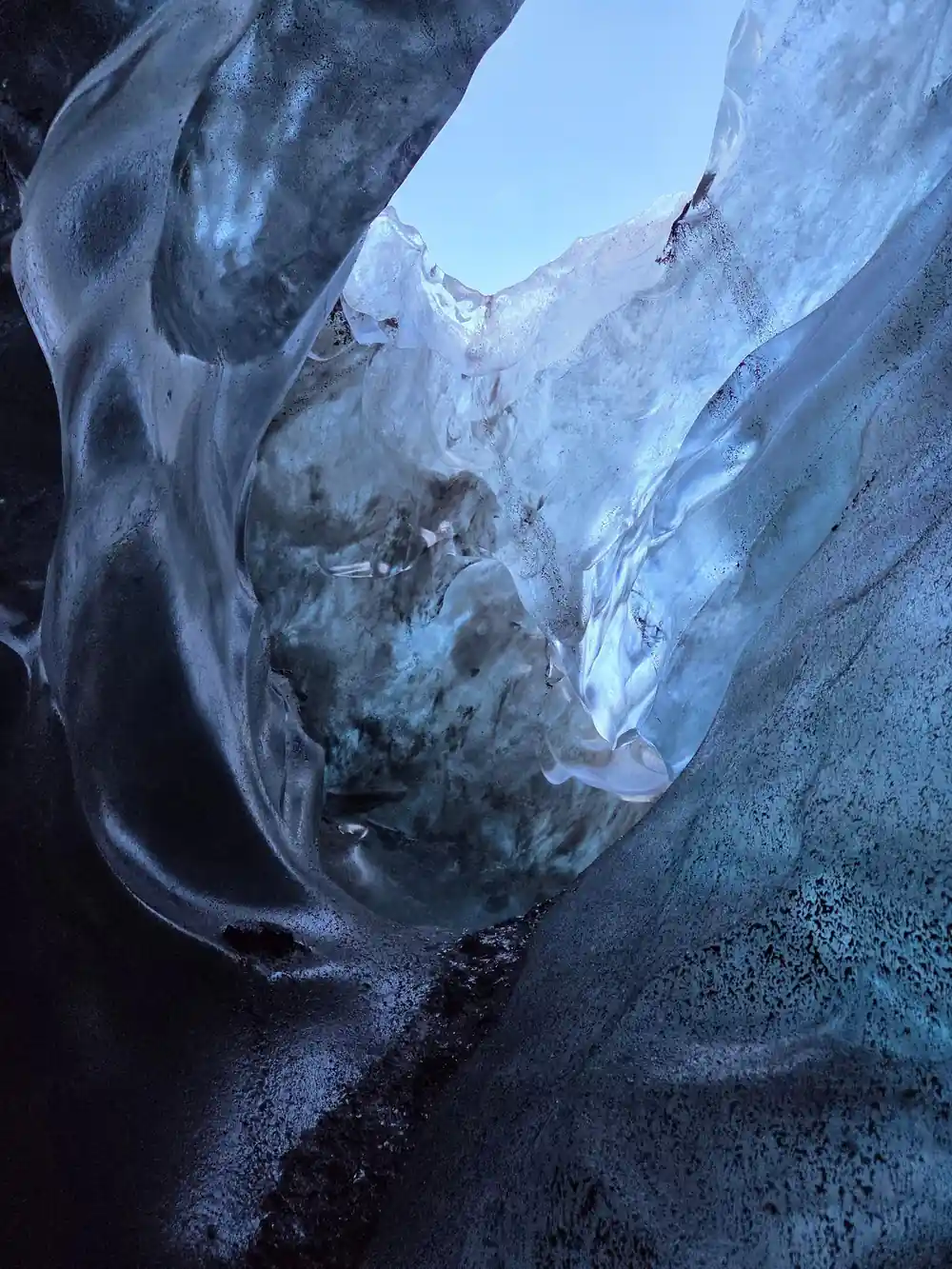 Ice cave passage with curved walls and bright opening