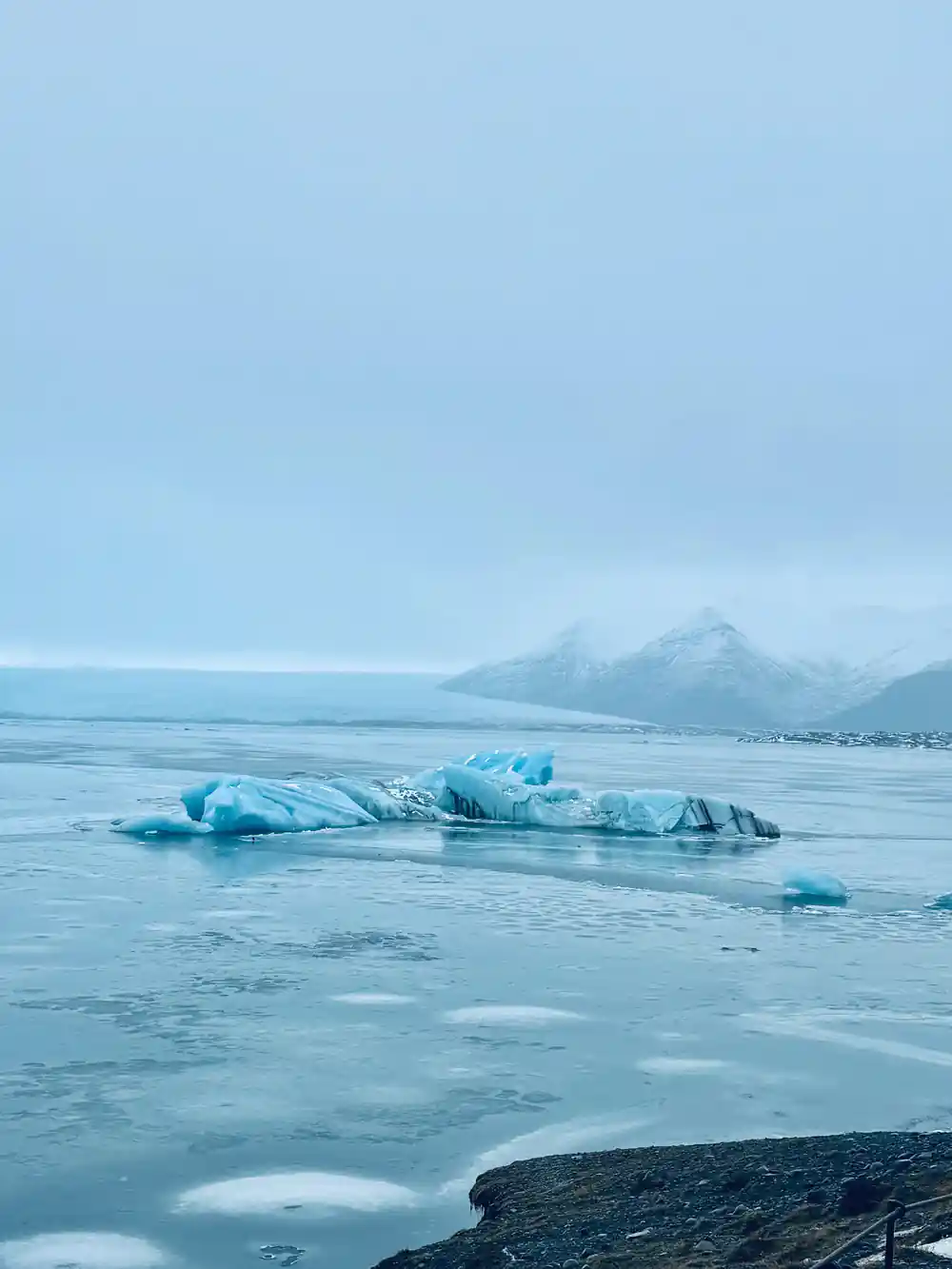 Icebergs floating in frozen lagoon with mountain