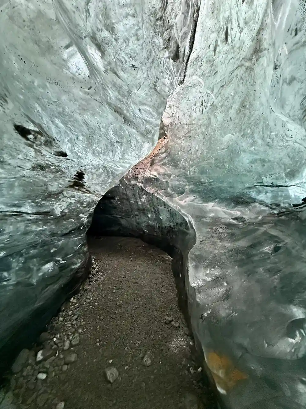 Interior of ice cave with turquoise walls and dark stone
