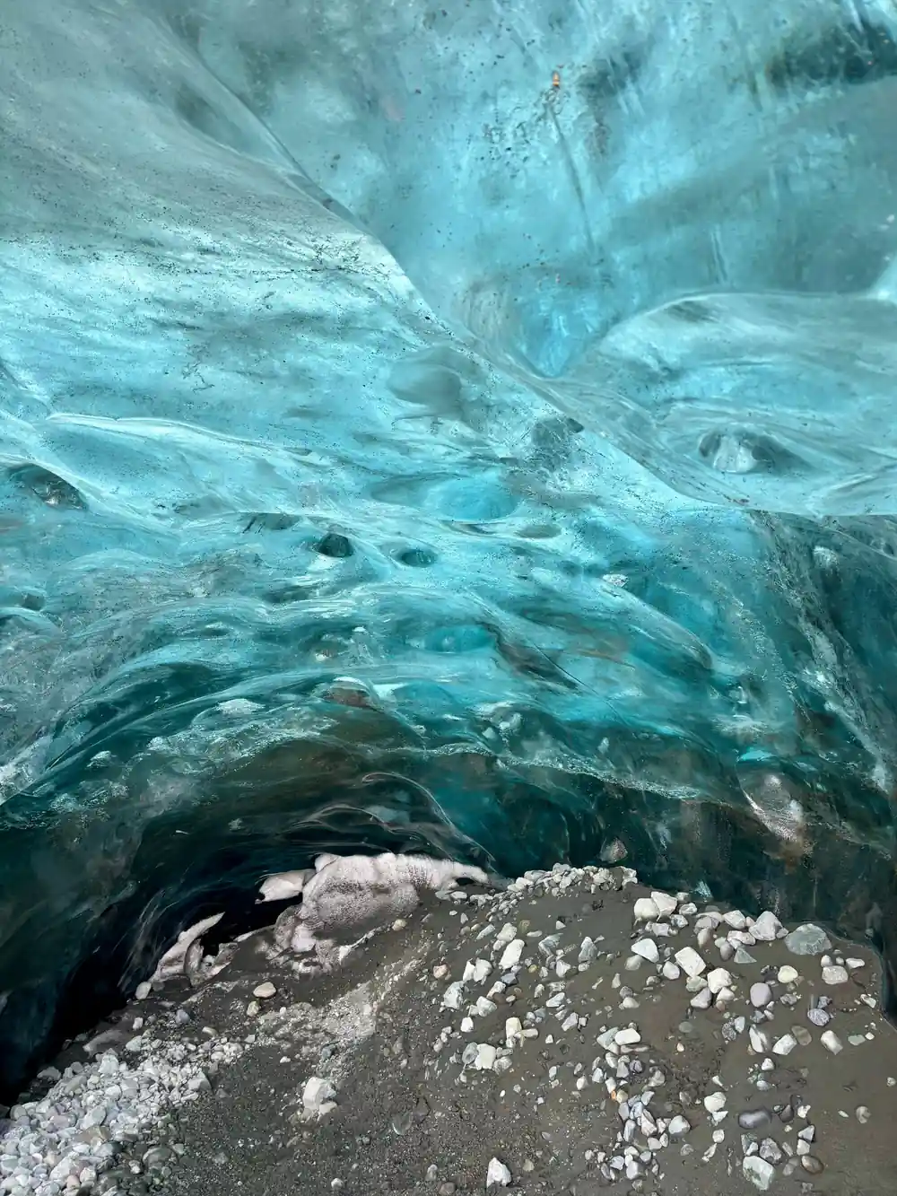 Layered pale blue ice formations in glacier cave