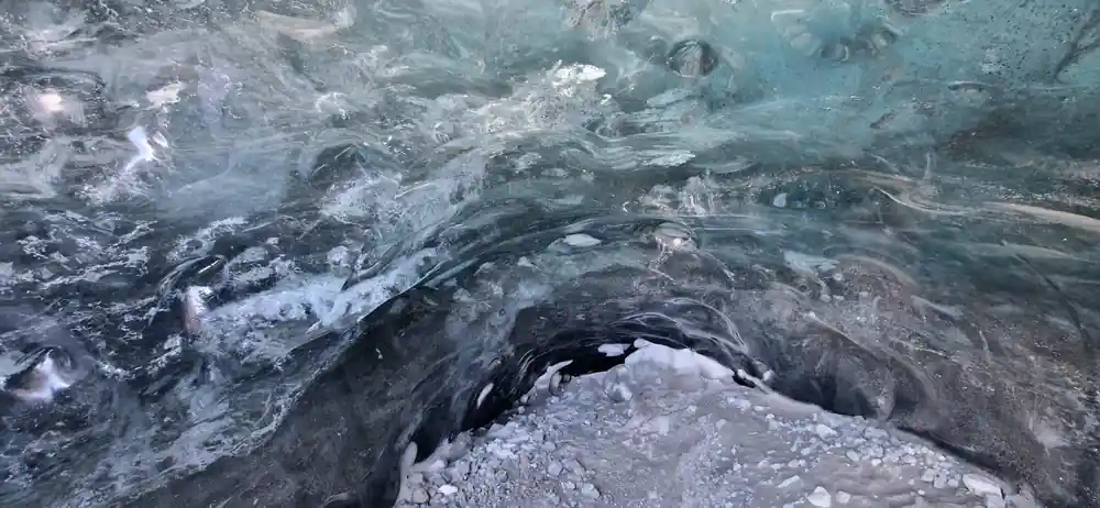Overhead view of dark ice cave tunnel and formations