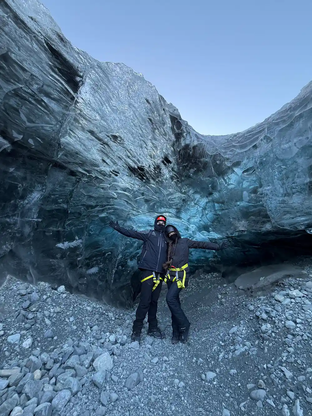 Person with arms spread inside blue glacial ice cave