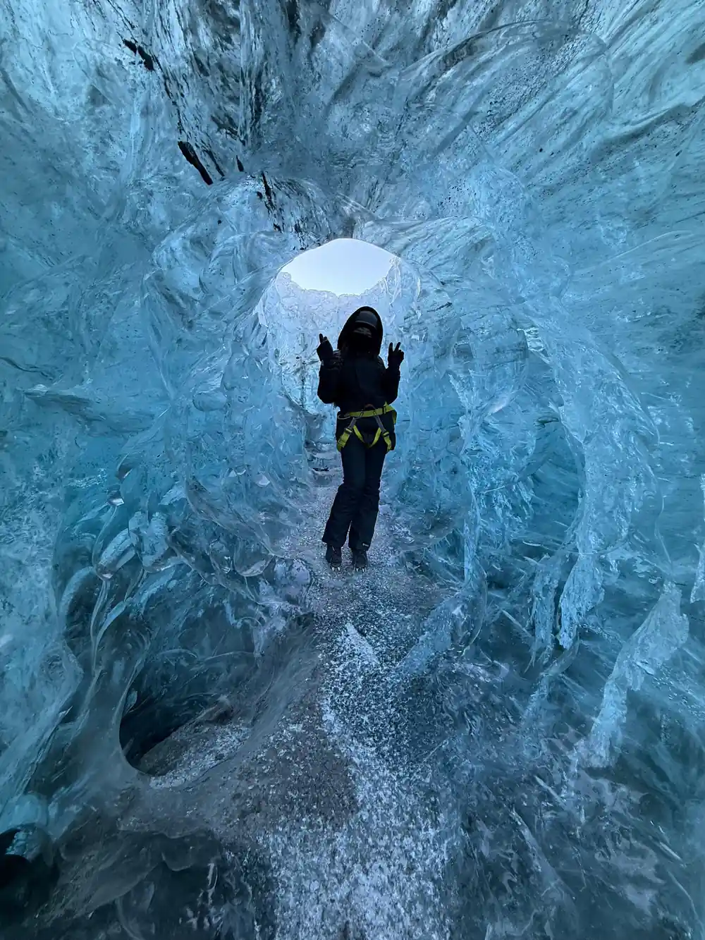 Person walking through narrow passage of blue ice walls