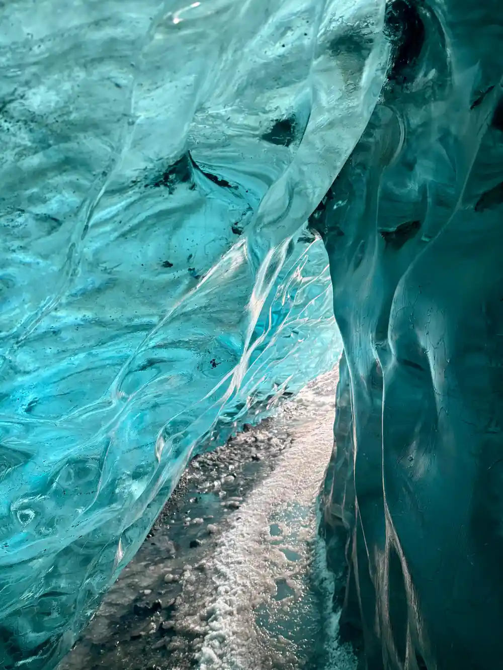 Swirled turquoise ice patterns above gray rocky base