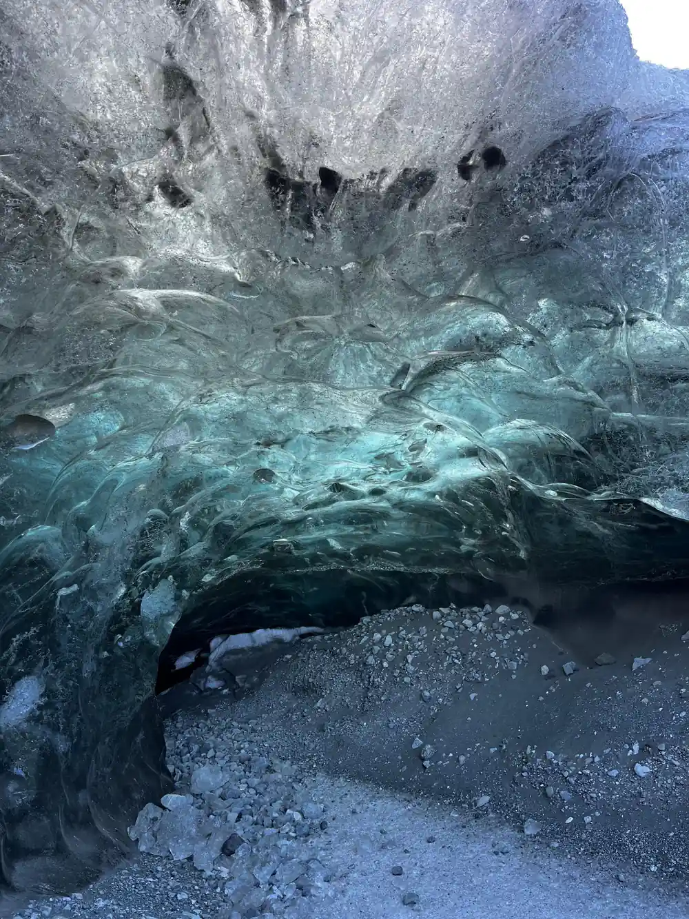 Translucent blue ice cave with dark cavern opening